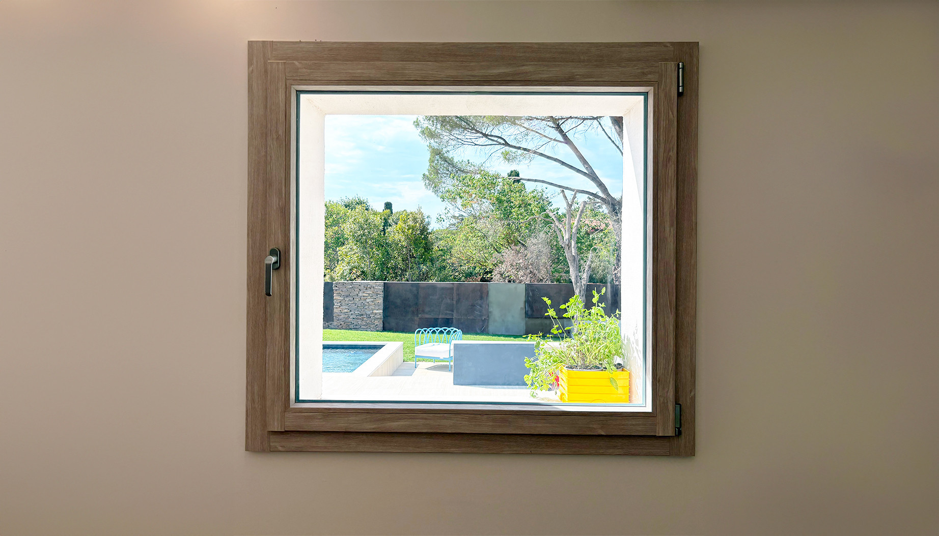 Ein Fenster von 10 paesaggi rahmt den Pool, den blauen Sessel und den Garten